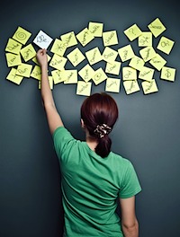 A woman organises her thoughts using yellow post-it notes on a wall